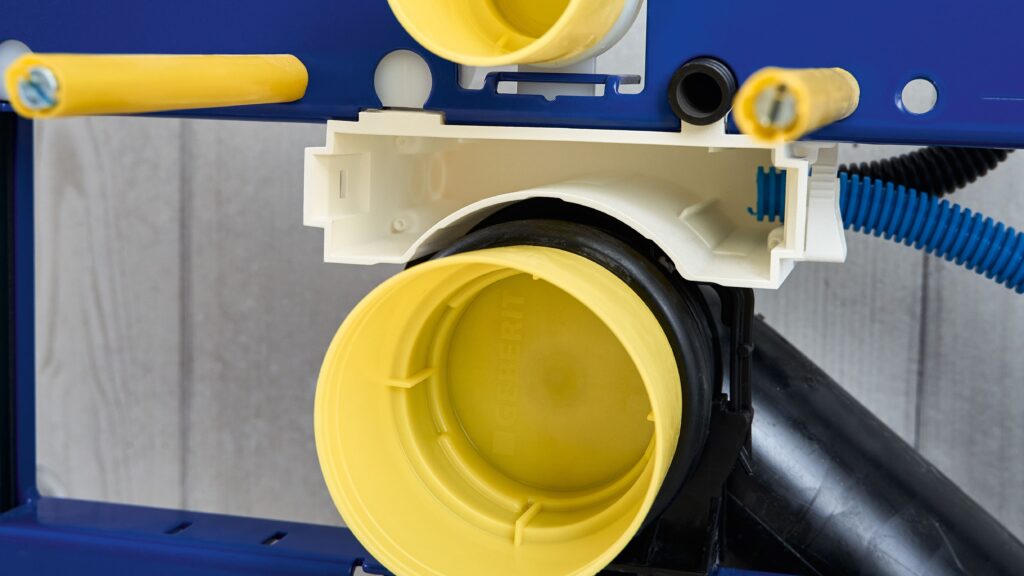 Zwischen Spülwassereinlaufrohr und WC-Ablaufstutzen: Für die Power & Connect Box ist eine Rohbaubox (weiß) Voraussetzung für anschließbare Leerrohre und die spätere Elektroinstallation. Bild: Geberit